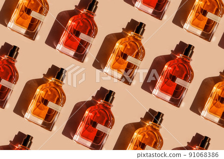 Pattern of different perfume bottles on a pastel beige background in the sunlight. Flat lay, top view. Luxury presentation mockup. Red, yellow and orange samples of aroma water 91068386