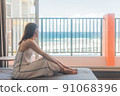 A girl traveling alone to Okinawa looks at the sea at a hotel 91068396