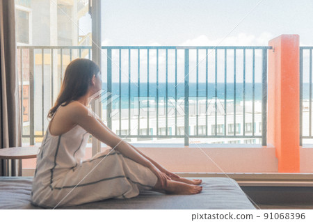 A girl traveling alone to Okinawa looks at the sea at a hotel 91068396