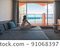 A girl traveling alone to Okinawa looks at the sea at a hotel 91068397