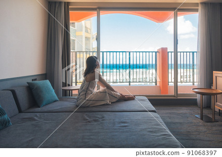 A girl traveling alone to Okinawa looks at the sea at a hotel 91068397