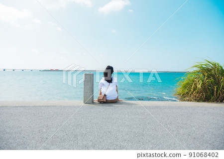 A girl traveling alone to Okinawa looks at the sea 91068402