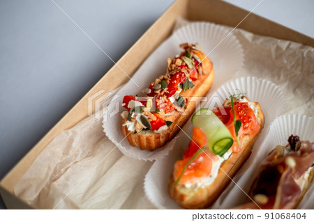 Eclairs with salmon, fresh vegetables and herbs, gourmet snacks. 91068404