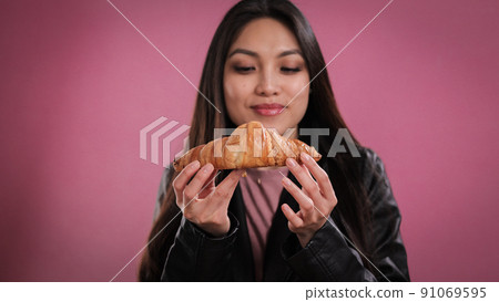 Young pretty woman eats a French croissant Young pretty woman eats a French croissant 91069595