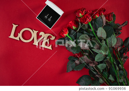Jewelry set of golden earrings in a gift box and red roses on re Jewelry set of golden earrings in a gift box and red roses on re 91069936