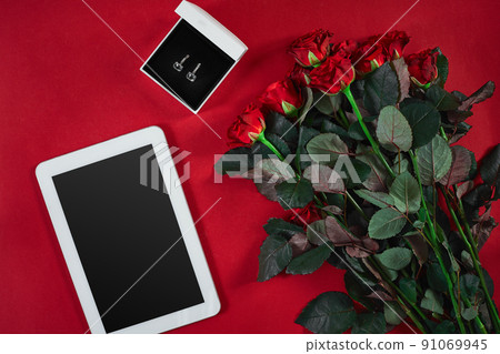 Jewelry set of golden earrings in a gift box and red roses on re 91069945