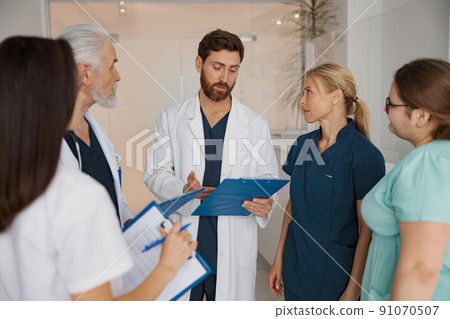 Group of doctor colleagues discussing patient diagnosis stand in clinic hall 91070507