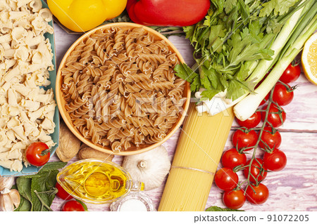 Italian pasta with vegetables, olive oil, spices on a wooden background, top view 91072205
