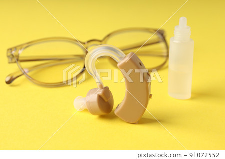Concept of health care with hearing aid on yellow background Concept of health care with hearing aid on yellow background 91072552