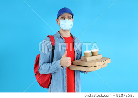 Delivery man with food on blue background 91072583