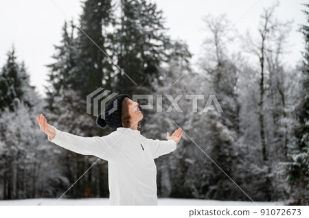 Peaceful woman standing in winter nature with her arms spread Peaceful woman standing in winter nature with her arms spread 91072673