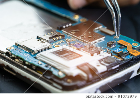 Technician repairing inside of mobile phone by soldering iron. Integrated Circuit. the concept of data, hardware, technology. Technician repairing inside of mobile phone by soldering iron. Integrated Circuit. the concept of data, hardware, technology. 91072979