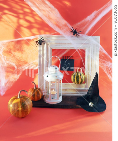 Halloween, a lantern with a burning candle, pumpkins, a witch's hat, against the background of a frame, cobwebs with spiders and magical shadows, the concept of interior decoration for the holiday 91073055