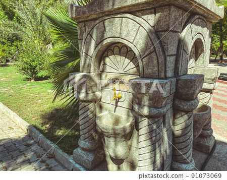 faucet in muslim temple, islamic religion. a stone sink stands on the street. a silver faucet for washing the hands of parishioners. natural stone sink faucet in muslim temple, islamic religion. a stone sink stands on the street. a silver faucet for washing the hands of parishioners. natural stone sink 91073069