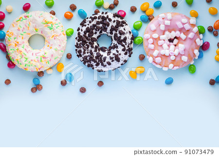 Set of different sweet glazed donuts with sprinkles and candy on blue background 91073479