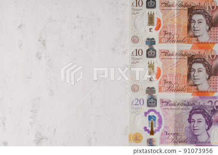 Pounds sterling. Cash UK. The latest design of the 10 and 20 pound notes with plastic inserts. On a gray textured background Pounds sterling. Cash UK. The latest design of the 10 and 20 pound notes with plastic inserts. On a gray textured background 91073956