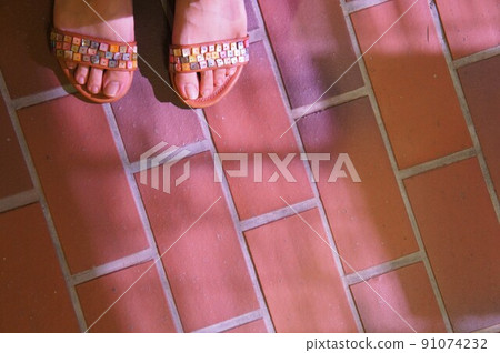 The feet of a woman wearing sandals at dusk in summer 91074232