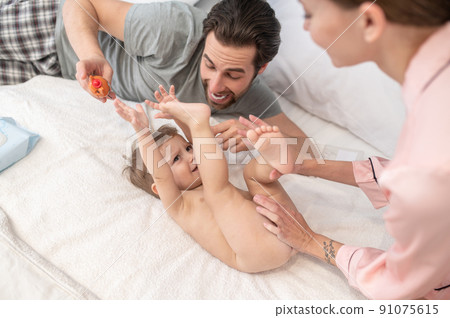 Mom caring of babys skin and dad with toy 91075615