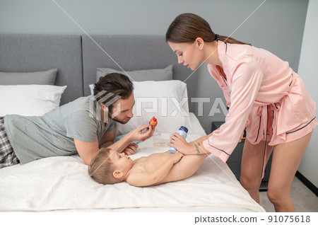 Woman holding powder near childs feet 91075618