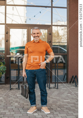 Man with suitcase standing outdoors smiling at camera Man with suitcase standing outdoors smiling at camera 91075633