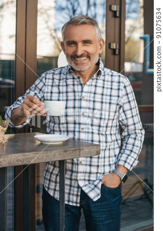 Man drinking coffee outdoors smiling at camera Man drinking coffee outdoors smiling at camera 91075634
