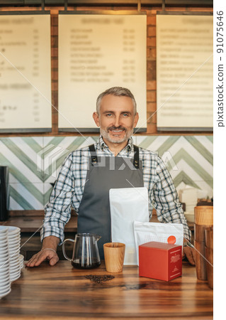 Man confidently looking at camera standing behind bar 91075646