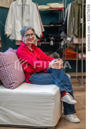 Woman looking at camera sitting on sofa in atelier 91075656