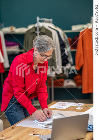 Woman carefully packing clothes bent over table Woman carefully packing clothes bent over table 91075662