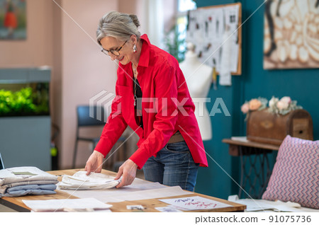 Woman standing near table folding clothes Woman standing near table folding clothes 91075736