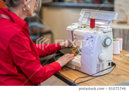 Woman sewing on machine sideways to camera Woman sewing on machine sideways to camera 91075746