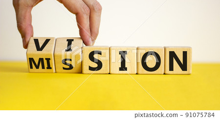 Mission vision symbol. Businessman hand turns wooden cubes and changes the word 'mission' to 'vision'. Beautiful yellow table, white background, copy space. Business and mission vision concept. Mission vision symbol. Businessman hand turns wooden cubes and changes the word 'mission' to 'vision'. Beautiful yellow table, white background, copy space. Business and mission vision concept. 91075784