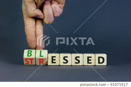 Blessed or stressed symbol. Businessman turns wooden cubes and changes the concept word Stressed to Blessed. Beautiful grey table grey background. Business blessed or stressed concept. Copy space. 91075817