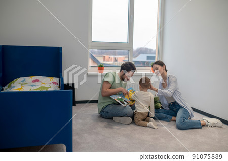 Young parents playing with their little son and showing him something Young parents playing with their little son and showing him something 91075889