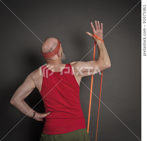 senior man is exercising with resistance band 91075961