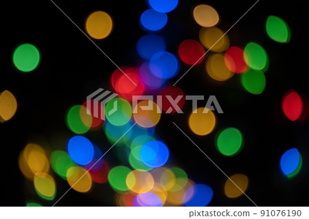 Defocused bokeh lights on black background, an abstract naturally blurred backdrop for Christmas eve or birthday party. Festive light texture. Colorful garland in blur. Overlay effect for design 91076190