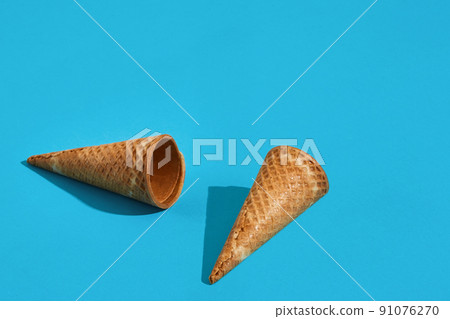 Two waffle ice cream cones with shadow on a blue background 91076270