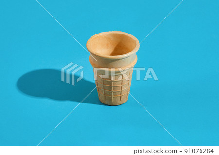 Waffle ice cream cones with shadow on a blue background Waffle ice cream cones with shadow on a blue background 91076284