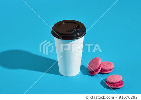 Hot coffee in white paper cup with black lid and pink macaroons 91076292
