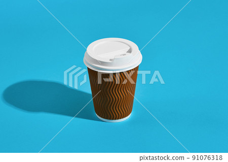 Hot coffee in brown paper cup with white lid on blue background 91076318