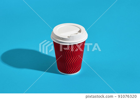 Hot coffee in red paper cup with white lid on blue background wi Hot coffee in red paper cup with white lid on blue background wi 91076320