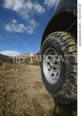 Big car wheel on mountains at day backdrop. Offroad 4x4 concept 91076519