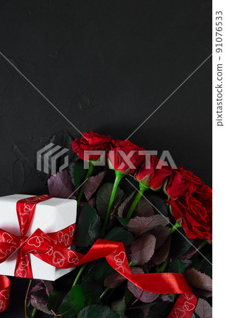 Top view fresh red rose flower and gift box on black deck with e Top view fresh red rose flower and gift box on black deck with e 91076533