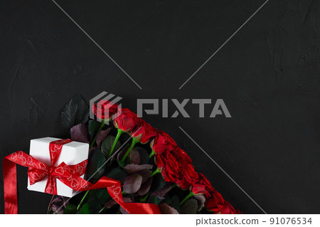 Top view fresh red rose flower and gift box on black deck with e Top view fresh red rose flower and gift box on black deck with e 91076534
