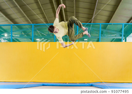 Teenage boy jumping on trampoline park in sport center Teenage boy jumping on trampoline park in sport center 91077495