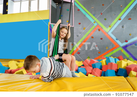 Children playing with soft cubes in the dry pool in play center. playground with foam blocks in trampoline club 91077547
