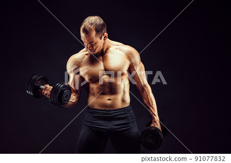 Powerful man doing the exercises with dumbbells. Photo of young man with good physique isolated on black background. Powerful man doing the exercises with dumbbells. Photo of young man with good physique isolated on black background. 91077832