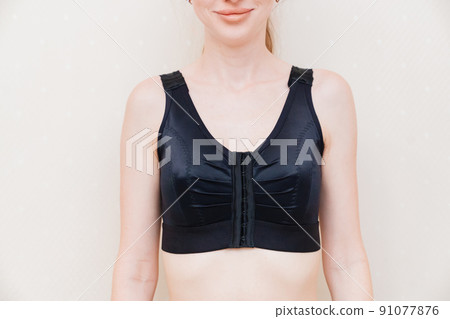 A young woman in black compression underwear after mammoplasty. A young woman in black compression underwear after mammoplasty. 91077876