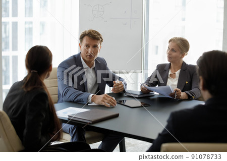 Middle-aged boss in suit lead corporate meeting with staff Middle-aged boss in suit lead corporate meeting with staff 91078733