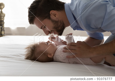 Loving young father touch his lovely baby lying on bed 91078777