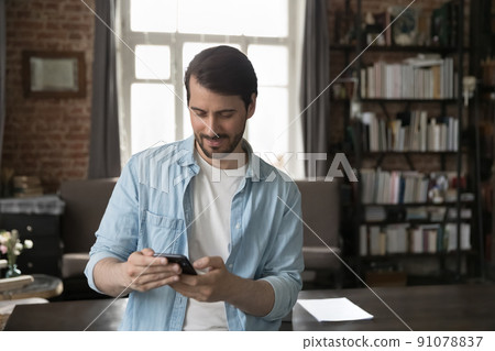 Man use smartphone standing in home office with modern smartphone Man use smartphone standing in home office with modern smartphone 91078837